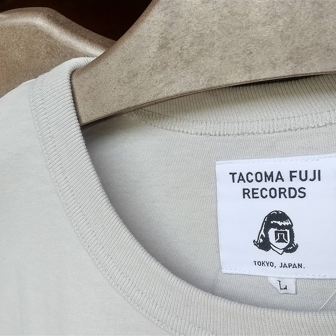 【TACOMA FUJI RECORDS】 T-shirt入荷しましたこれからの季節、何枚あってもイイですね今回もストーリーがおもしろい( 原文お借りしますm(_ _)m )#薪ストーブ#薪ストーブのある暮らし #山の暮らしのお手伝い#八ヶ岳#原村#tacoma#tacomafujirecords#tshirt️Downward Bound designed by Jerry UKAI️(dedicated to Mr. Warren Harding and Mr. Royal Robbins)「あぁ、ジェリーをダウンワードバウンド式ゾーンシステム*に当てはめるなんてバカバカしくてやめたのさ…。」とあるレジェンドクライマーはそう語った。10代後半でトリプルクラウンを達成、コンチネンタル・ディバイド・トレイルの名物ガイドとなり、小さな体で山道を軽快に歩く姿から「マウス」と呼ばれた若き日のジェリー・マルケス。写真嫌いだったと言われるその頃の姿を記録した写真は驚くほど少ないが、ロッククライマーとしてヨセミテで活躍していた頃の貴重な1枚の写真が何故か長野県白馬で発見された。今となってはみんなの人気者、ジェリーマルケスとは思えない、鼻っ柱の強さと可愛げのなさに「これがあのマルケス？」と真贋が騒がれたが、日本人で数少ない若き日のマルケスを知るジェリー鵜飼がいつもの口調で放った「ああ、これマルケスさんの若い頃だよね」の一言で一件落着＆マルケス認定。そんな一連の騒動を記念して、写真を発見した白馬を拠点とするQUIET SPORTがTACOMA FUJI RECORDSに別注をかけて作られTシャツです。*ウォレン・ハーディングの著書「墜落のしかたおしえます」の付録ページで紹介された独特な人格グレーディングシステム。偉大なクライマーの理想像をゾーン1とし、ダメなクライマーであるほどゾーン10に近い数値を叩き出すシステムで、実在するクライマーを下らない理由でボロクソにこき下ろしたことで有名。＊このストーリーはフィクションです。